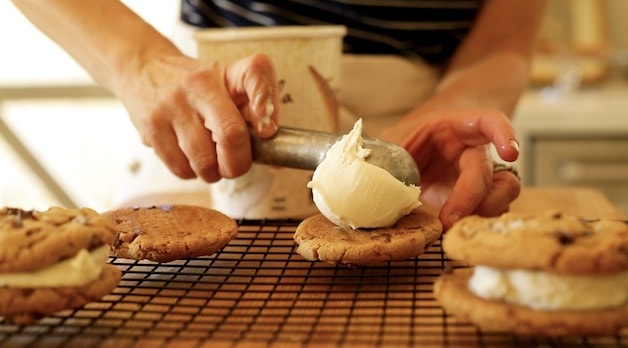 Placing a scoop of vanilla ice cream on top of a chocolate chip cookie