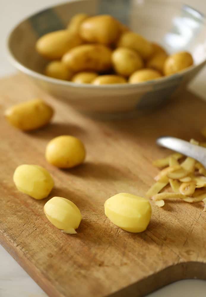 Dutch Baby Potatoes are a board being peeled before boiling. 