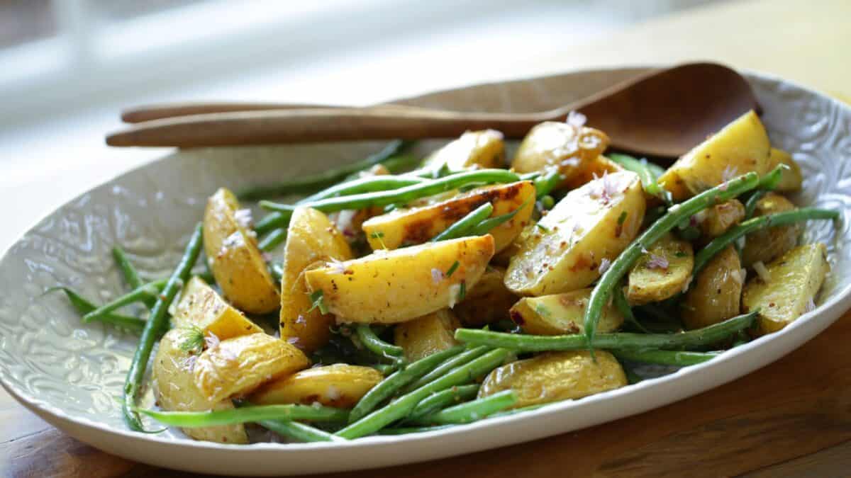 Potato salad with no mayo on a platter with green beans and vinagrette