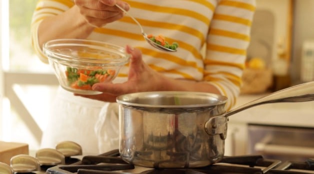 Adding frozen peas and carrots to pot