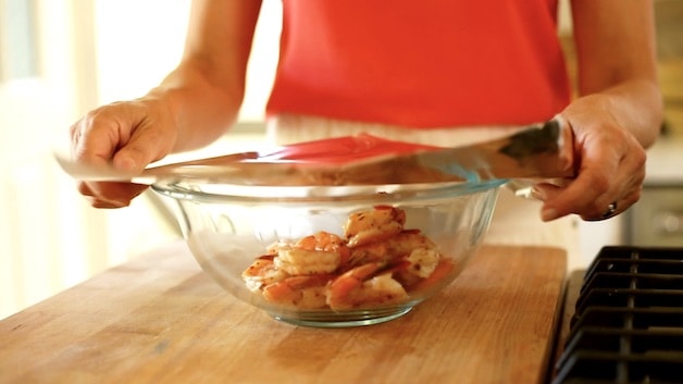 Cooked shrimp in a bowl being covered with aluminum foil
