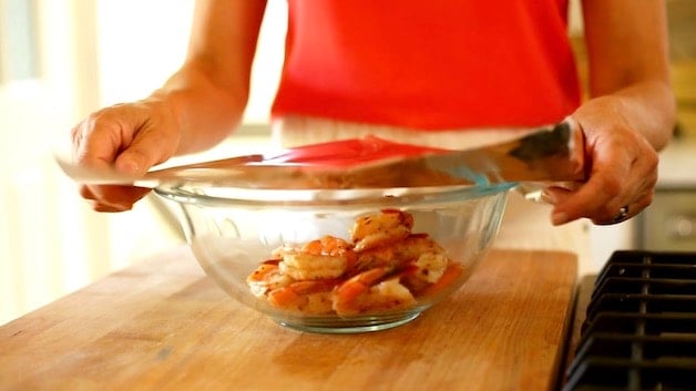 Cooked shrimp in a bowl being covered with aluminum foil