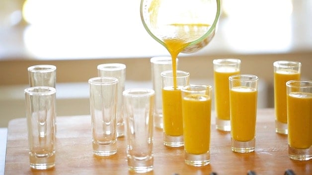 Pouring yellow gazpacho soup into small shot glasses