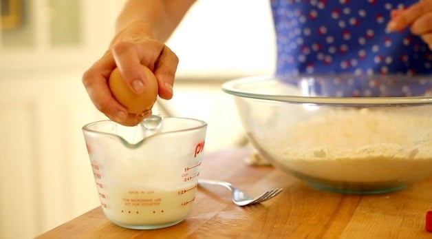 Adding egg to measuring cup filled with cream