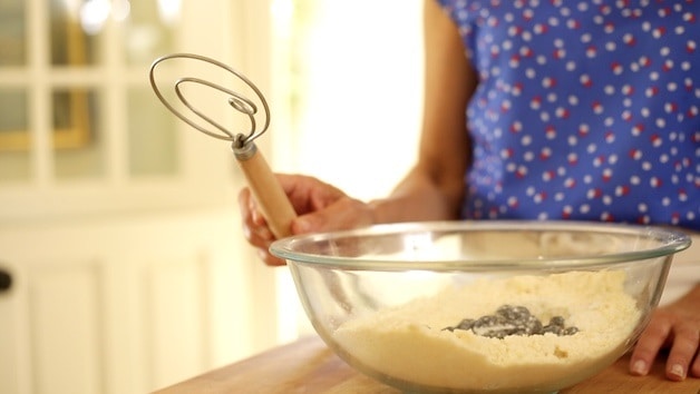 Dansk visp och en skål med scone deg med tillsatta blåbär