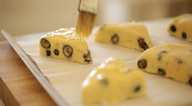 Brushing blueberry scones with egg wash before baking