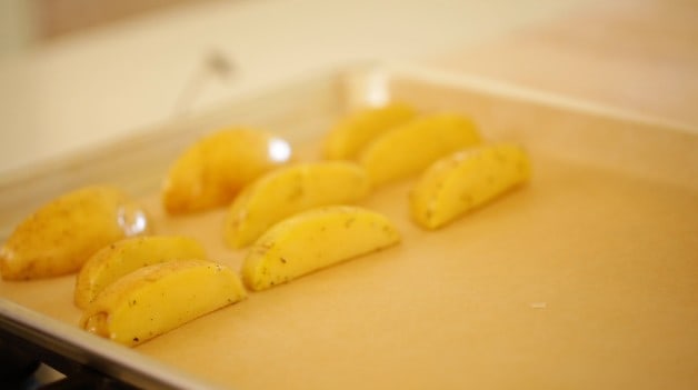 Potatoes sliced on a baking sheet lined with parchment paper