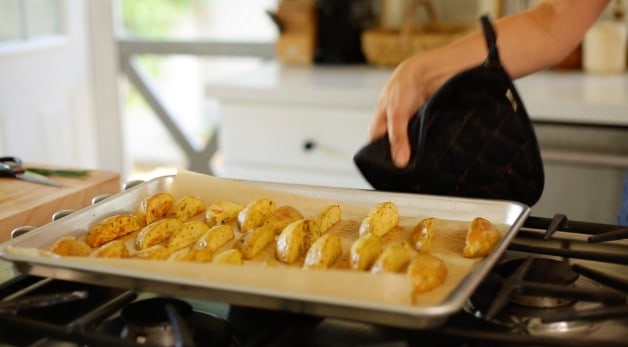 Roasted Potato Wedges on a baking sheet lined with parchment paper cooling on cooktop