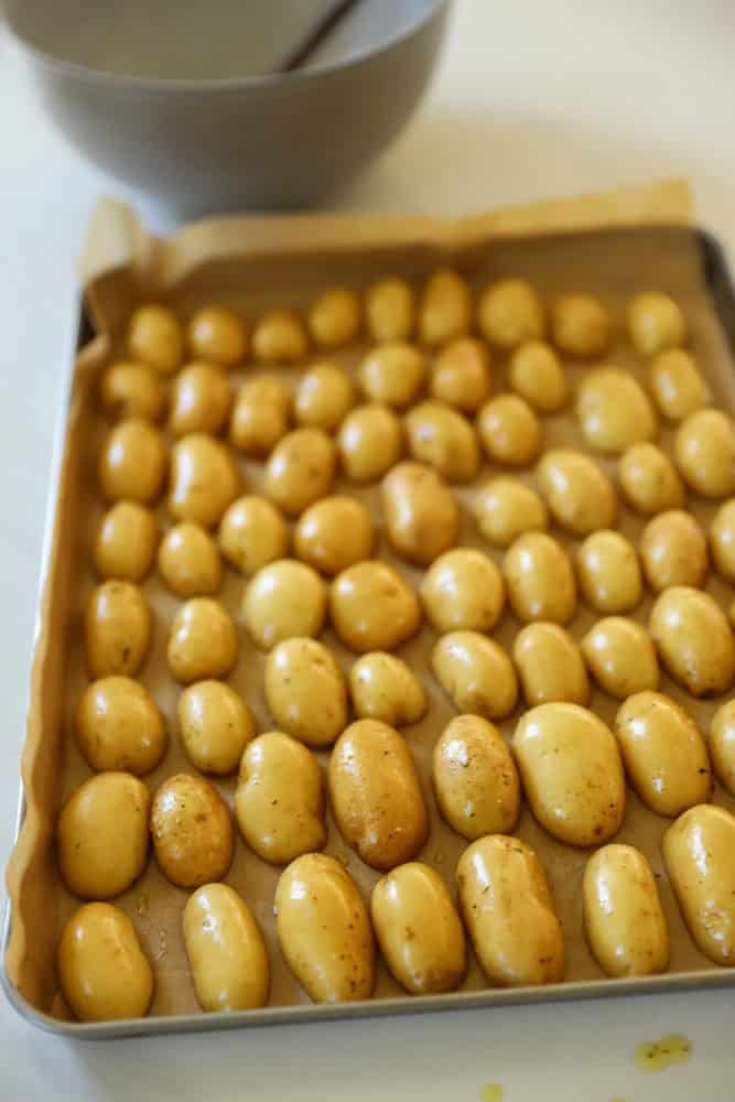 Sliced yukon gold potatoes on a baking sheet with parchment paper.