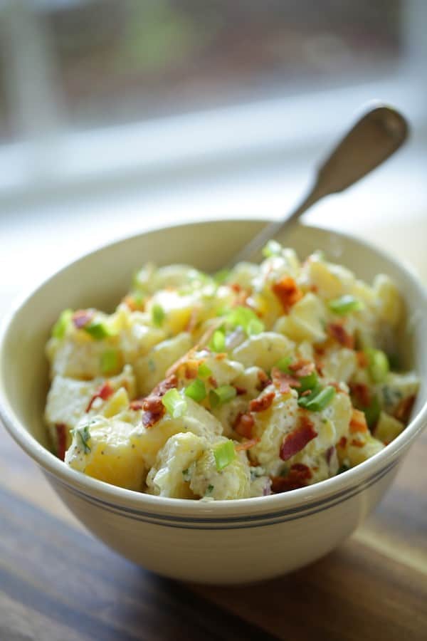 Close up of Traditional Potato Salad in white bowl with spoon