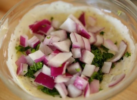 Chopped purple onion and seasoning in mayonnaise mixture for traditional potato salad