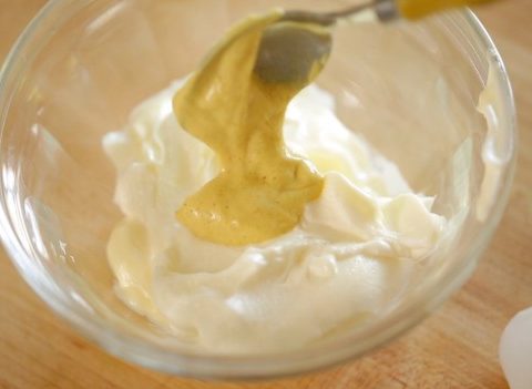 Adding Dijon mustard to bowl of mayonnaise and sour cream
