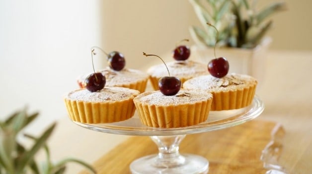 Cherry Bakewell Tart Recipe with cherry on top on cake stand