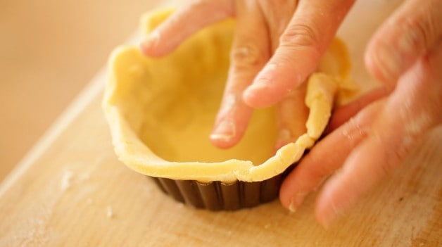 Montage de la pâte sur la boîte à tarte pour la recette de tarte aux cerises Bakewell