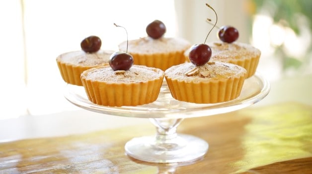 Cherry Bakewell Tart Recept cseresznyével a tetején a tortaállványon közelről