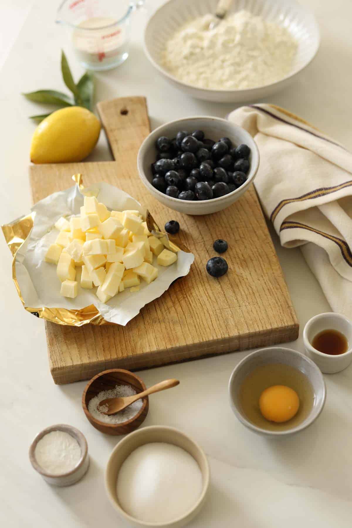 Blueberries, Butter, Flour, Heavy Cream and Egg along with other scone ingredients on a counter.