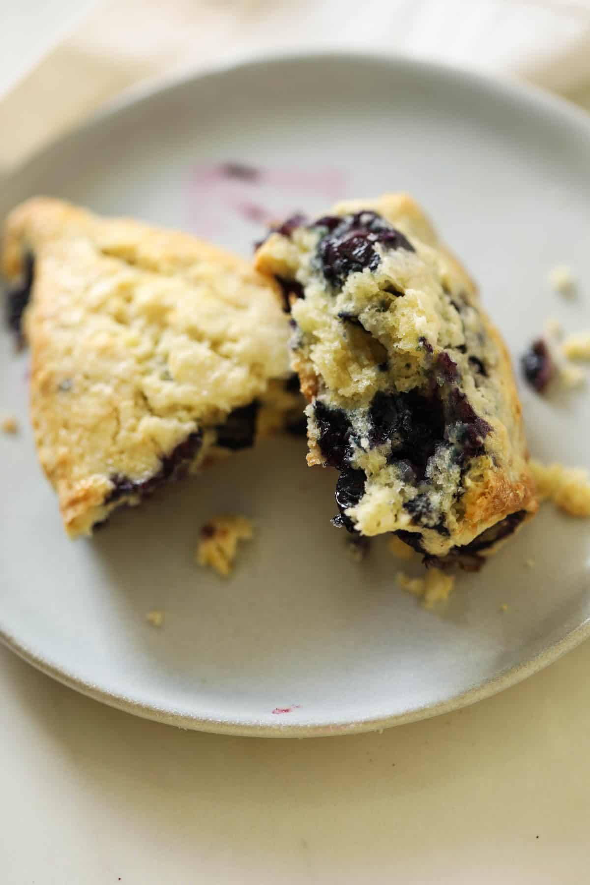 flaky scone broken in half and placed on a plate.