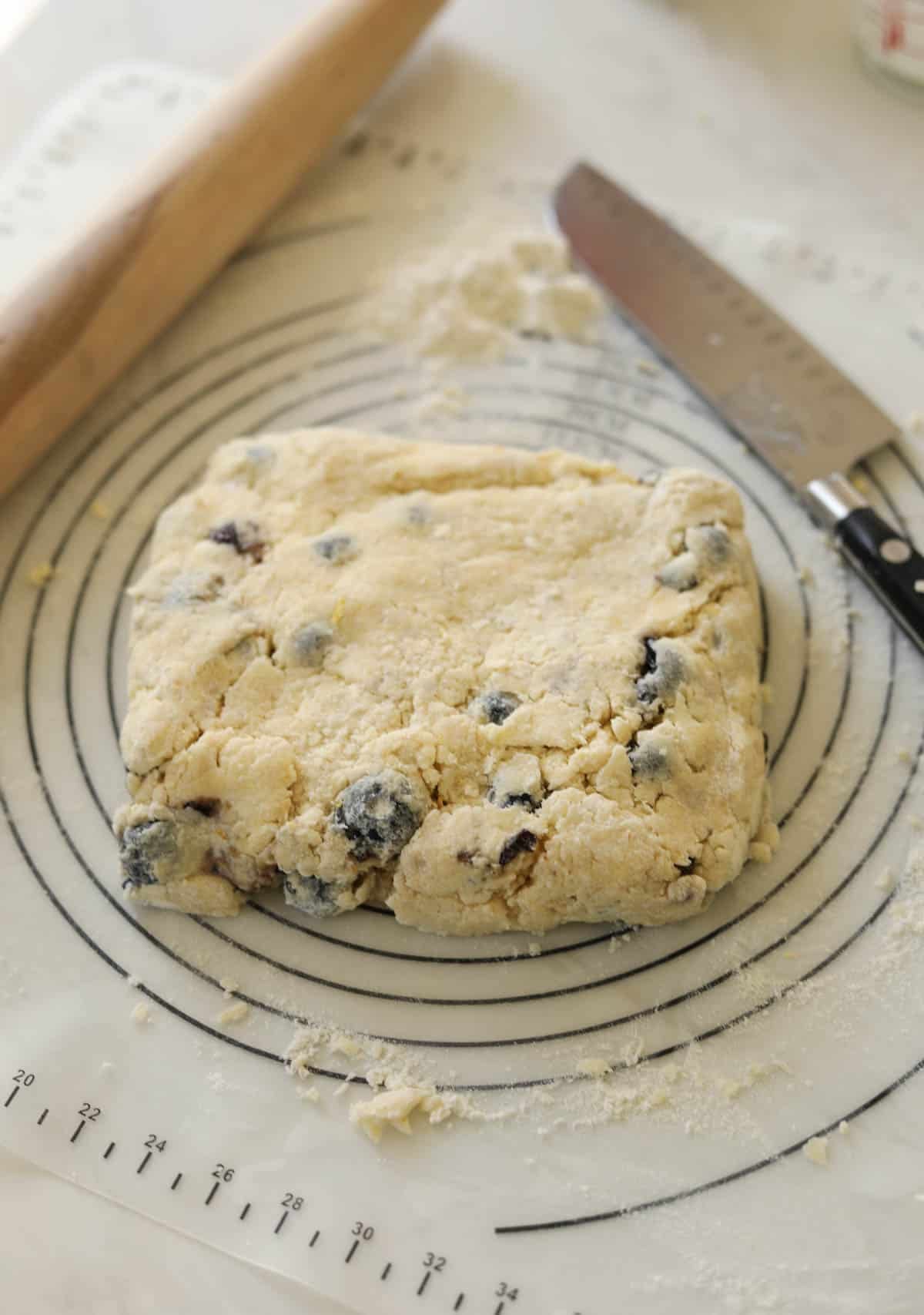 A mass of blueberry scone dough formed into a square.