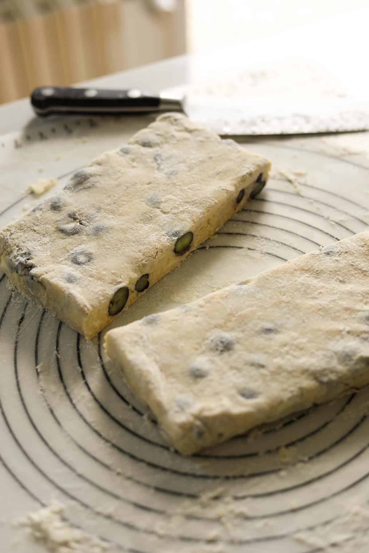 A scone dough square cut in half showing blueberries.