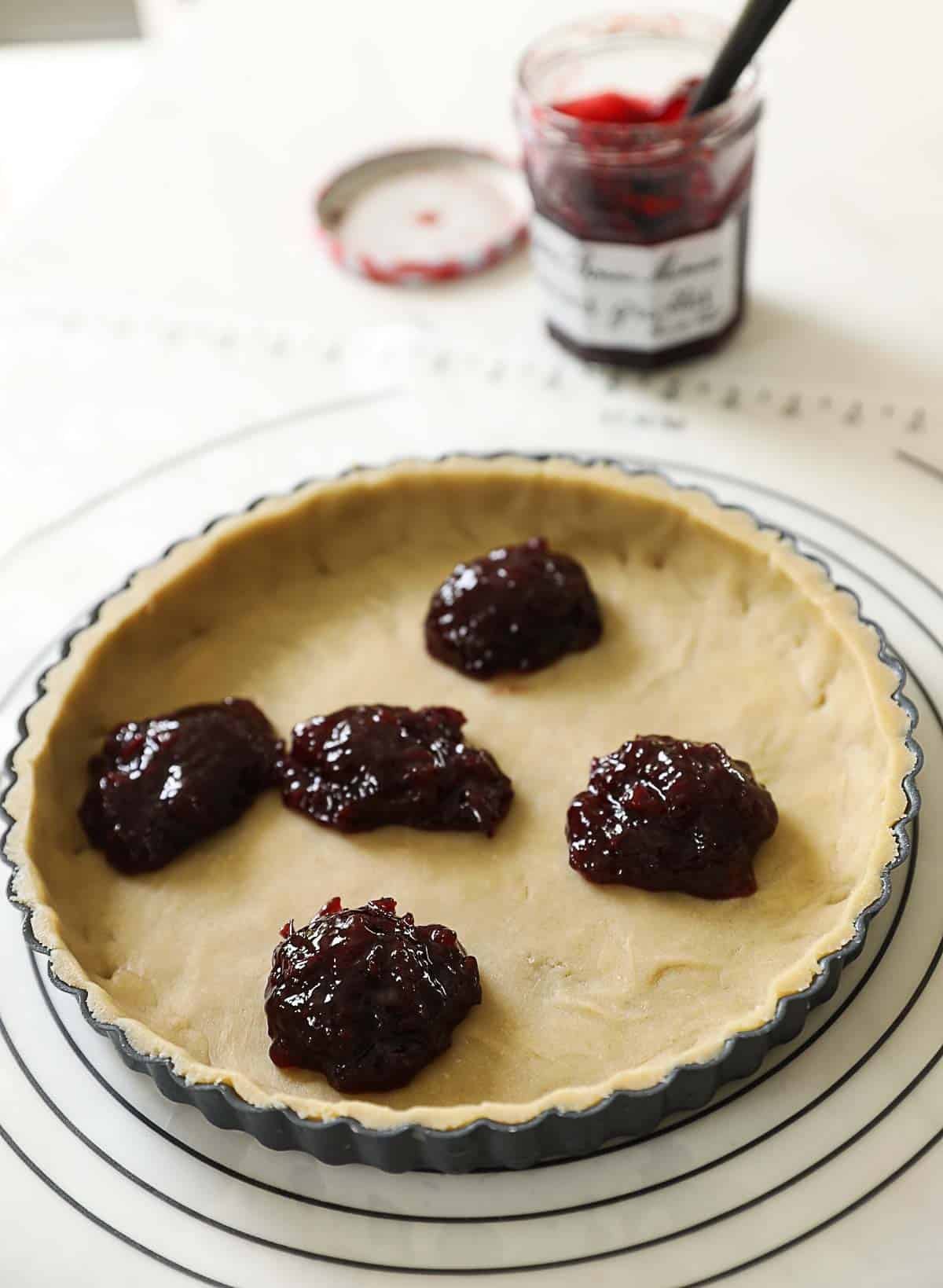 Cherry Jam in the base of a layer of pastry in a tart tin.