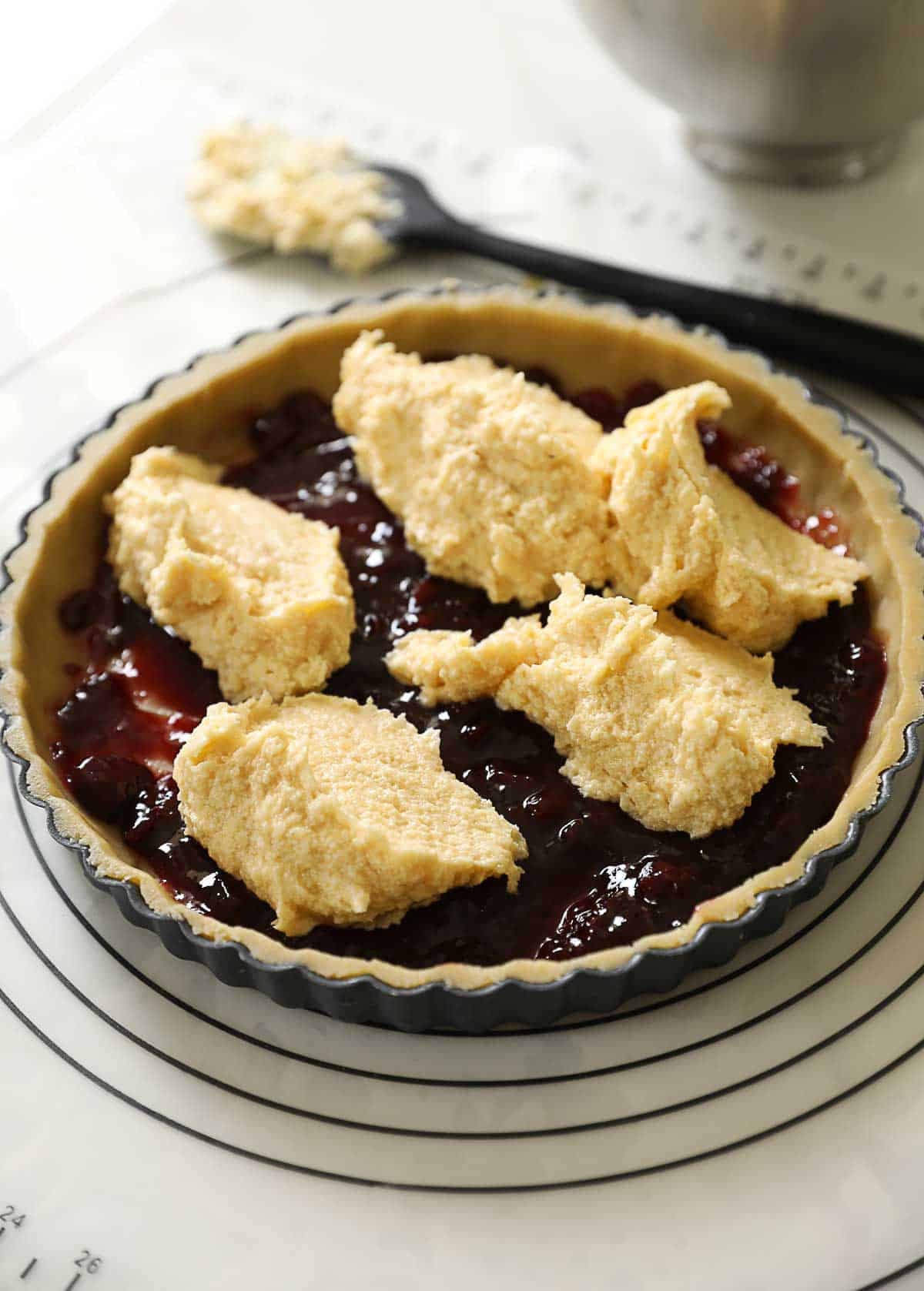 A layer of cherry jam, covered by dollops of almond, fragipane filling.