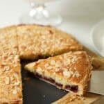 a slice of a Cherry Bakewell Tart in a tart tin, showing the cherry jam.