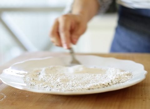 Whisking Italian herbs into flour with a fork on a plate