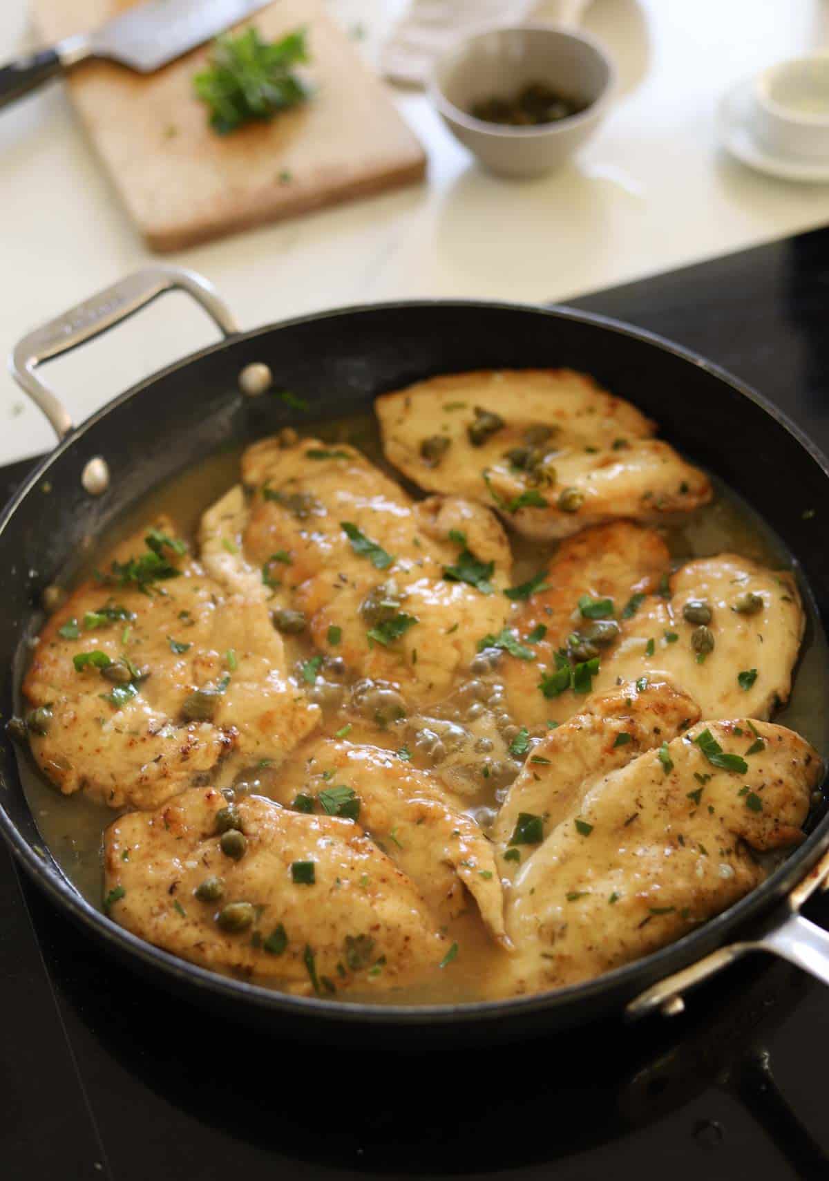 Chicken in a deep skillet with a lemon caper sauce on top