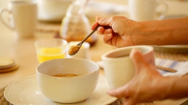 Adding brown sugar to bowl of oatmeal