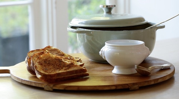 dutch oben and bowls and grilled cheese sandwiches on a large round board