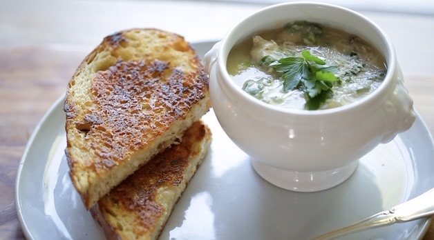 a bowl of white bean soup with sausage and kale and a grilled cheese sandwich
