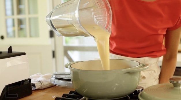 pouring blended white bean soup into a dutch oven