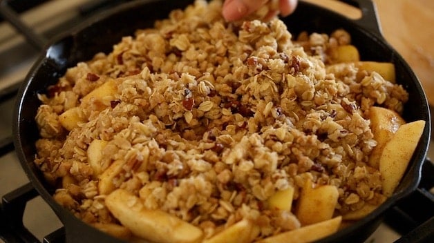 topping apples in a skillet with crisp topping