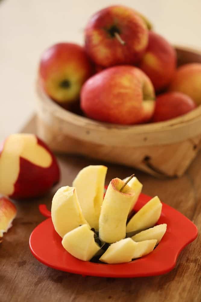 apples being sliced with an apple slicer.