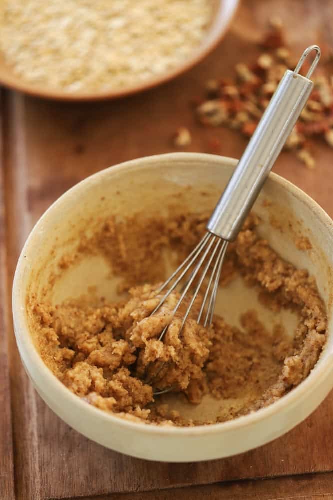 Butter, flour and spices stirred together to form a crumb topping in a bowl with a whisk.