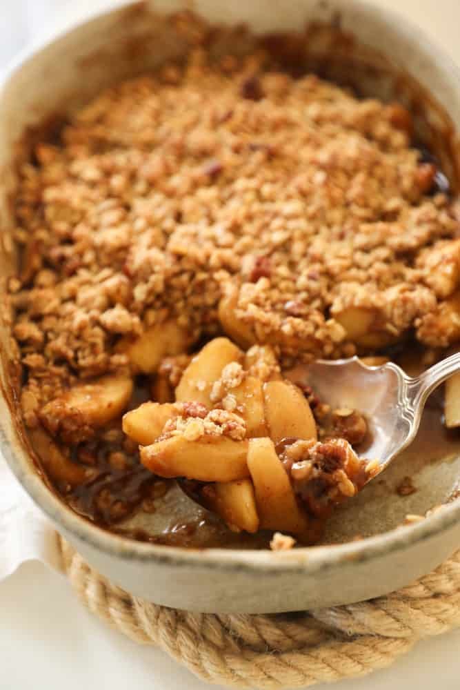 Apple Crisp in a oval casserole with a silver spoon.