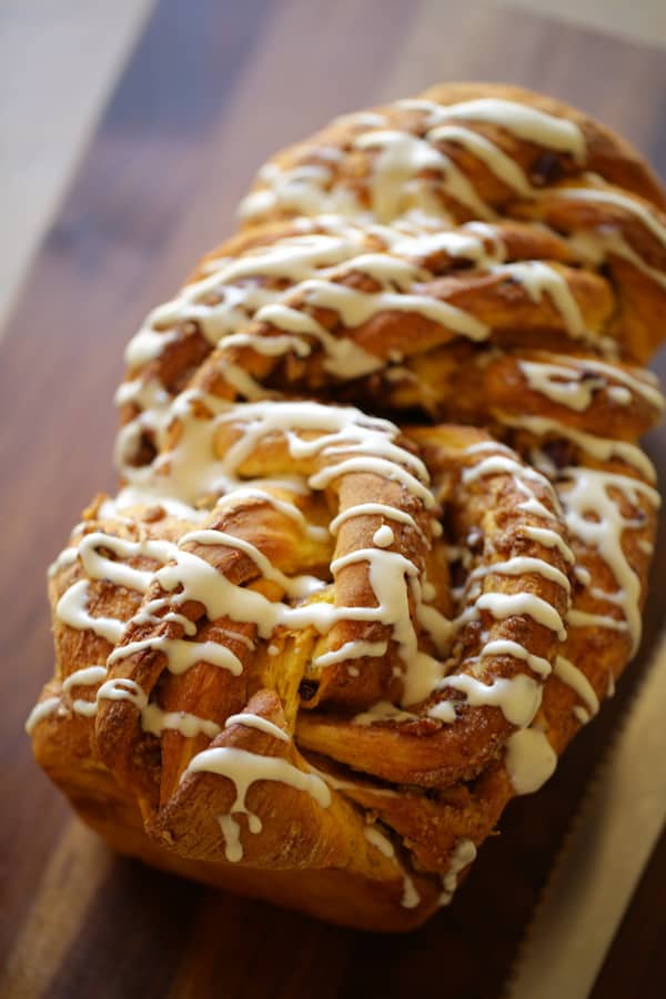 vertical image of a pumpkin cinnamon roll loaf on a cutting board