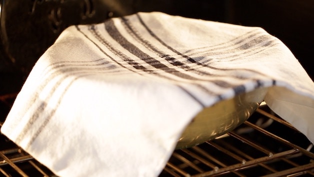 Dough Rising in oven in a bowl with a dishtowel on top