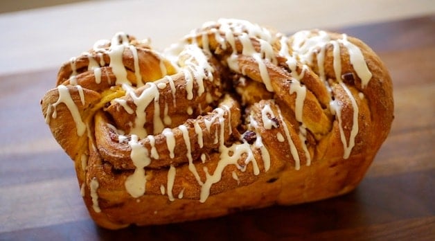 Pumpkin Cinnamon Roll Loaf with Cream Cheese Glaze on a cutting Board