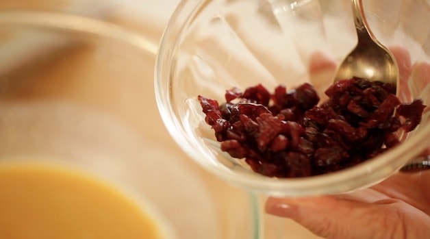 adding dried cranberries to bowl