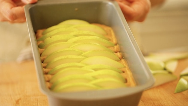 Green Pears arranged nicely on cake batter in a loaf pan 