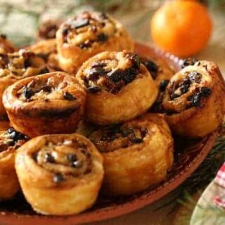 sticky buns on a terra cotta dish with evergreens in the background