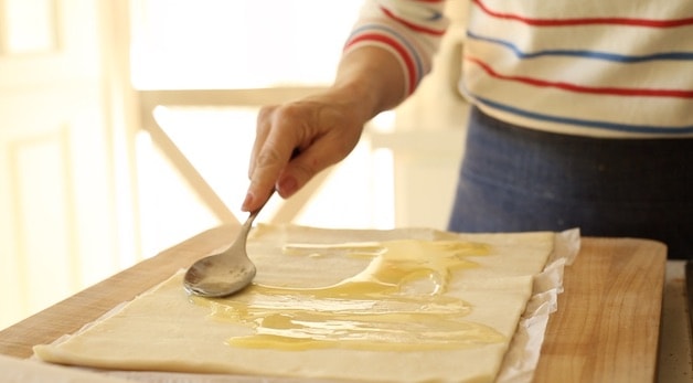 adding melted butter to a puff pastry sheet