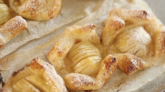 Baked apple pastries with powdered sugar on a baking sheet 