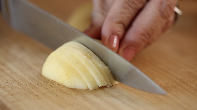 Slicing apple into ¼\" slices on cutting board