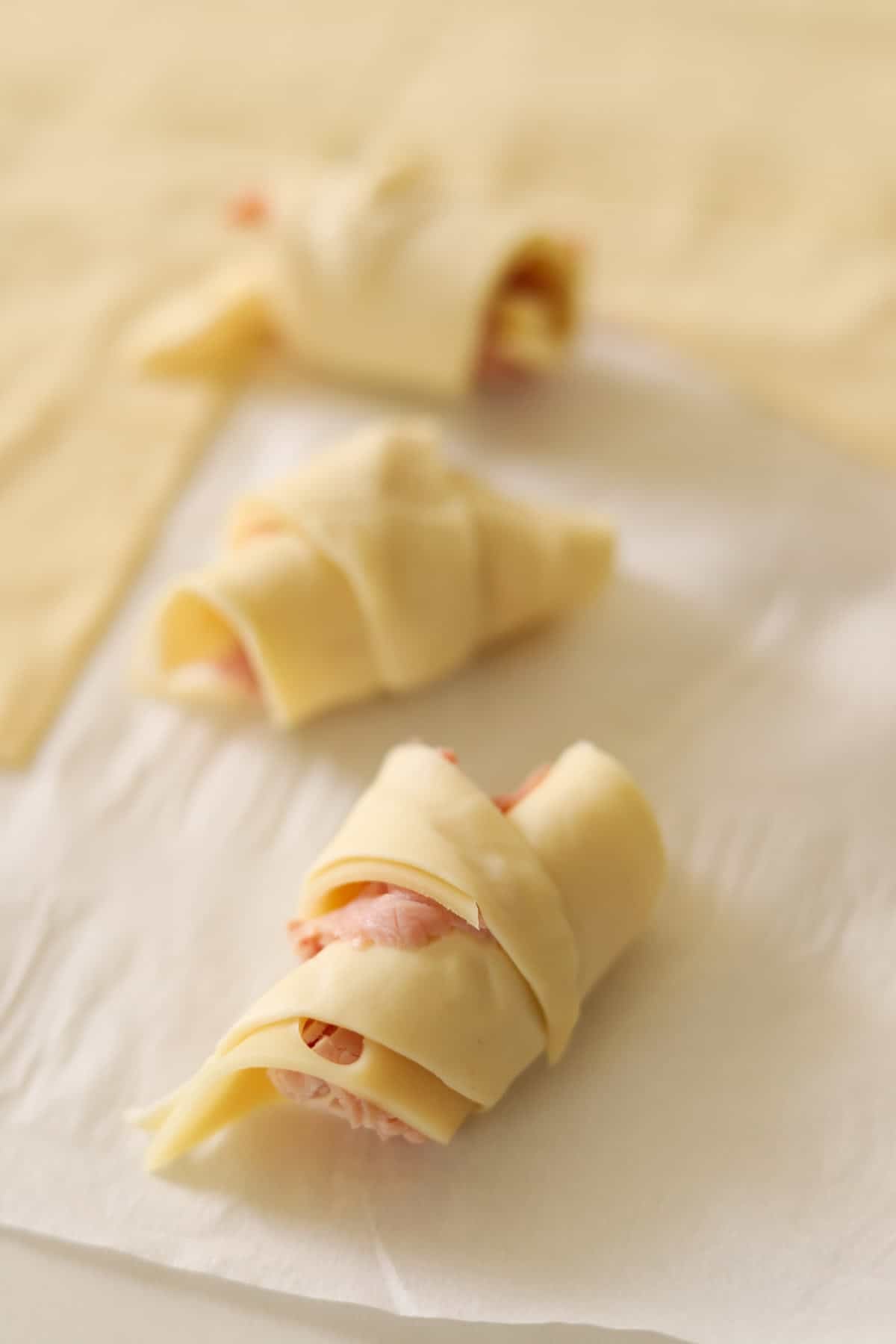 Mini ham and cheese croissants rolled up and ready to be baked.