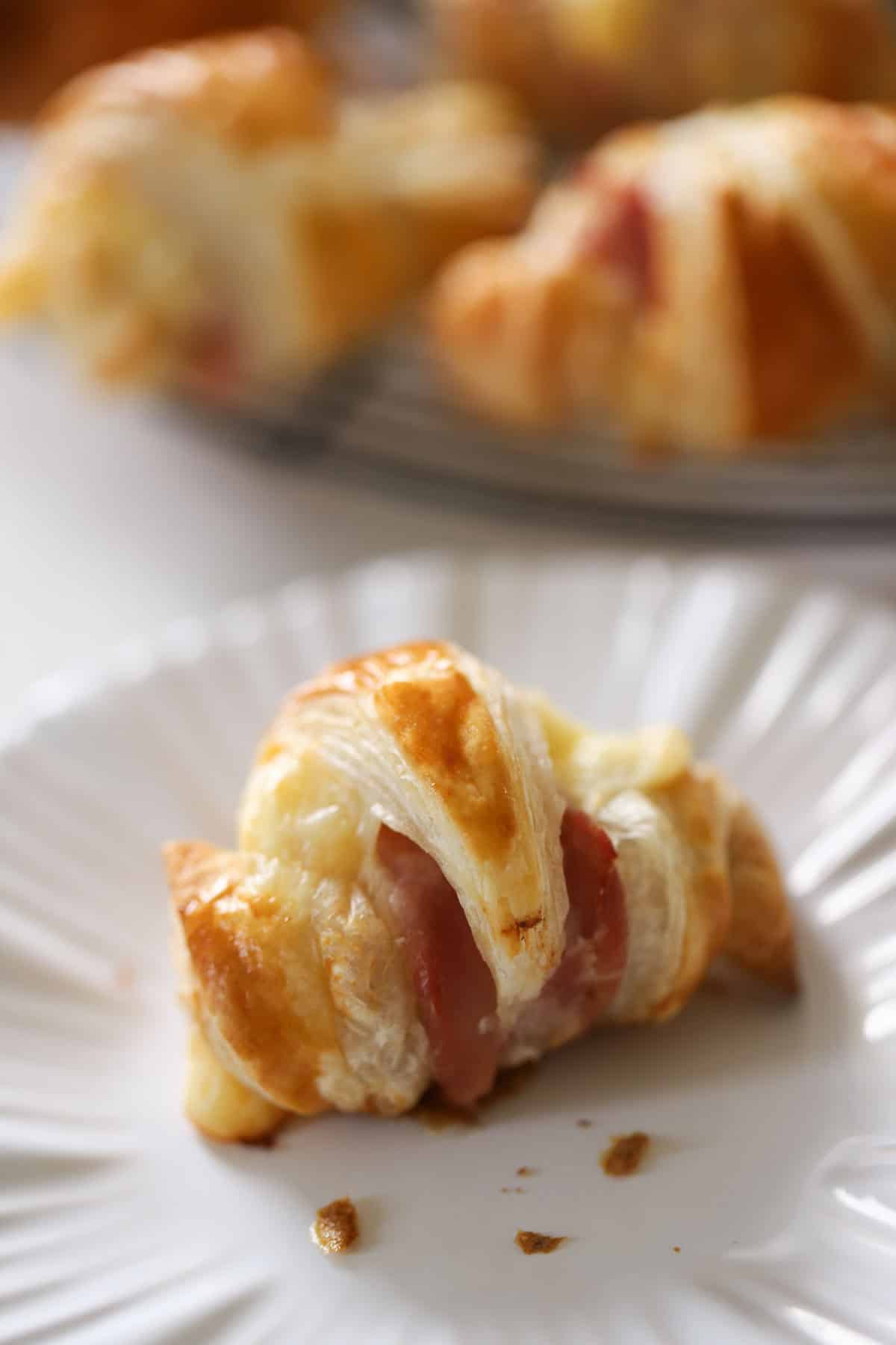 a mini ham and cheese croissant on a plate.