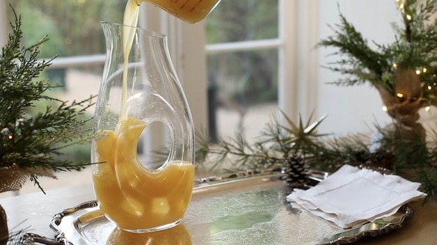 Pouring Pineapple Juice over Frozen Pineapple Juice into a Clear Carafe