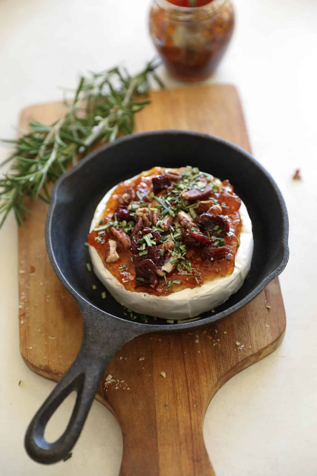 brie in a skillet with rosemary in background