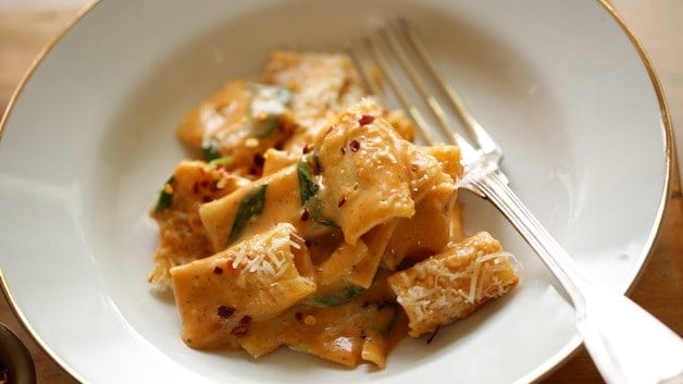 Creamy Sun Dried Tomato Pasta with spinach in a white bowl with fork